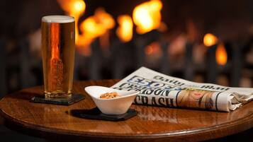 Ein Holztisch mit einem Bierglas, einer Schüssel Nüssen und einer Zeitung.
