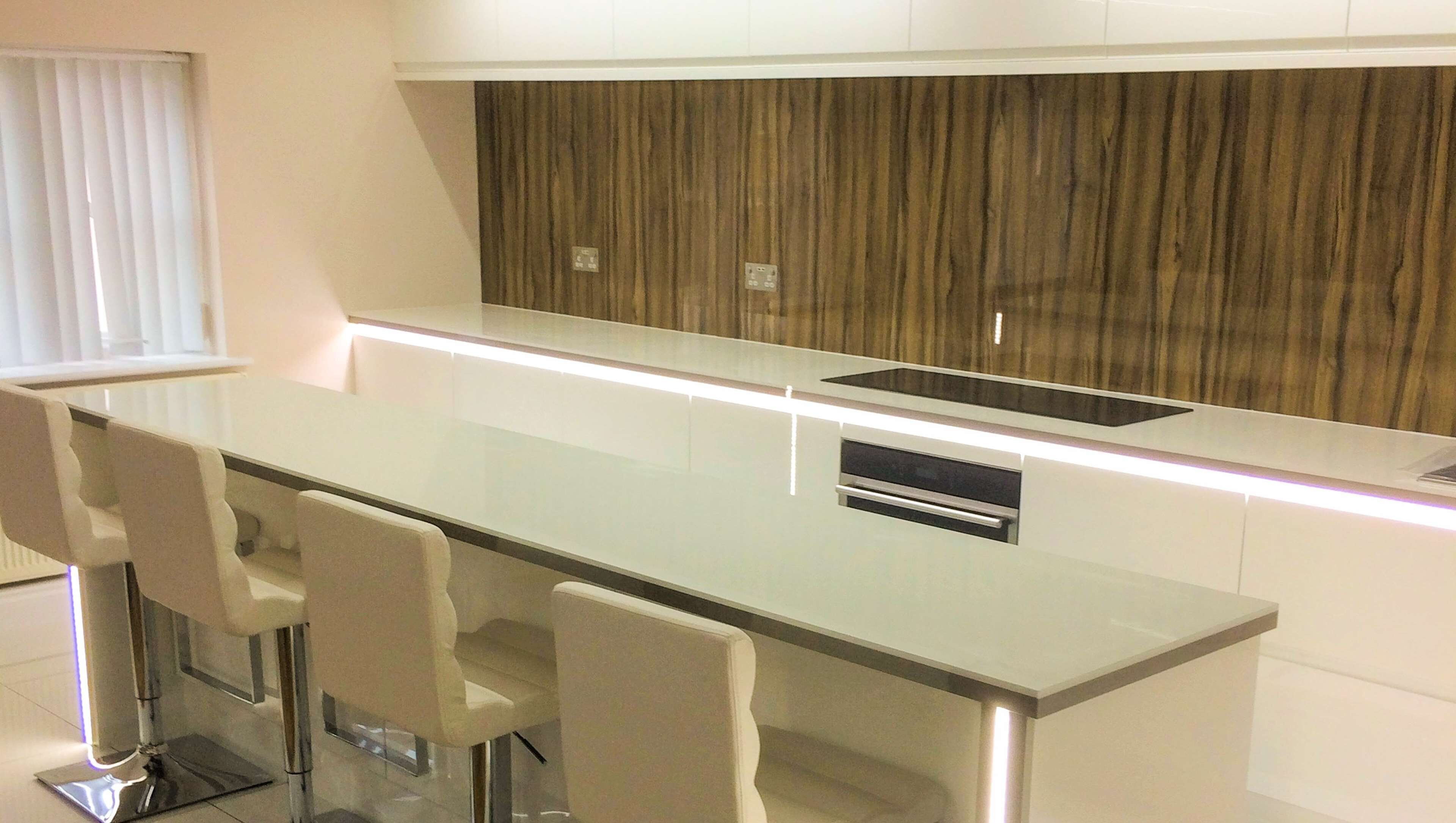 A modern kitchen with a central island, bar stools, and a wooden accent wall.