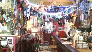 Un espace bar avec des tabourets en métal, un comptoir et divers éléments de décoration, dont un grand drapeau Union Jack.