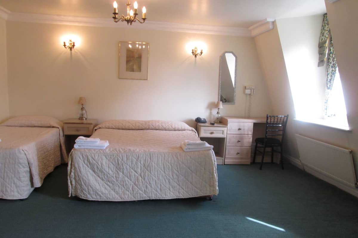 A bedroom with two beds, a desk, a chair, a dresser, and a mirror.