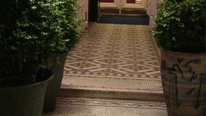 Un espace d’accueil avec une enseigne indiquant « Le Bar » et un escalier menant à une pièce aux rideaux rouges.