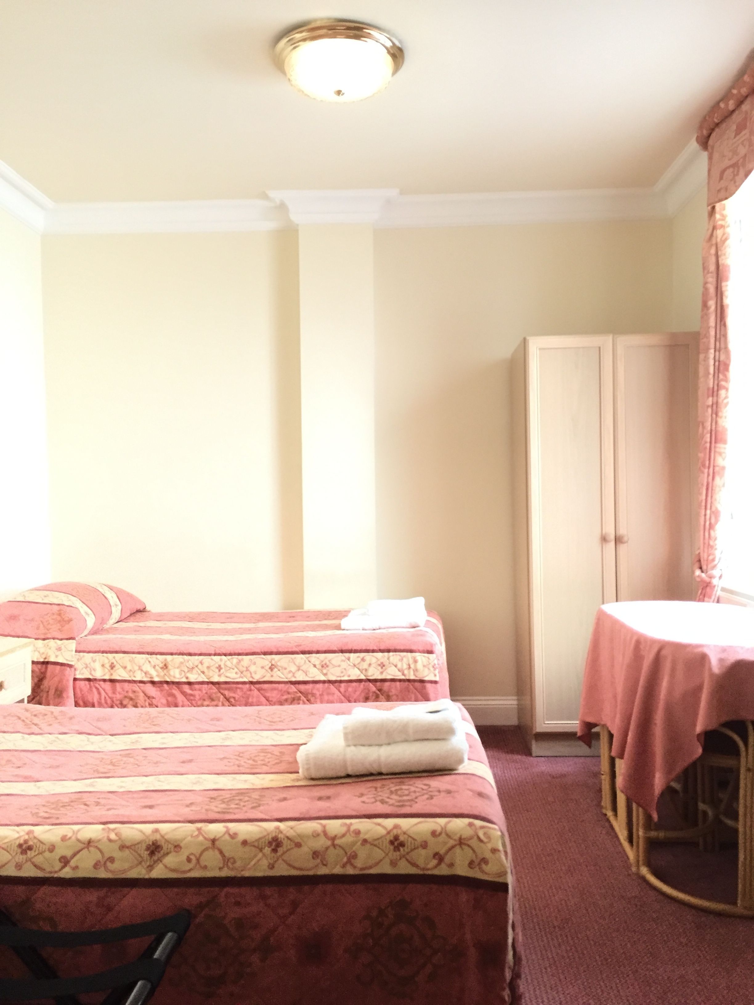 Een hotelkamer met twee bedden, een kledingkast, een tafel met tafelkleed en een stoel.