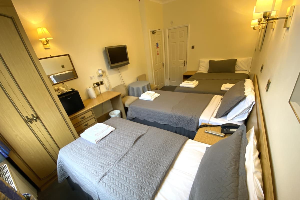 A hotel room with two beds, a TV, a desk with a lamp, and a wardrobe.