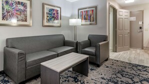 A modern hotel lobby with a grey sofa, two armchairs, a coffee table, and abstract art on the walls. - Best Western Allatoona Inn & Suites (Cartersville)