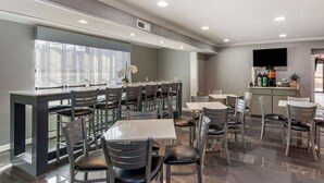 A modern dining area with multiple tables and chairs, a bar area, and a television mounted on the wall. - Best Western Allatoona Inn & Suites (Cartersville)
