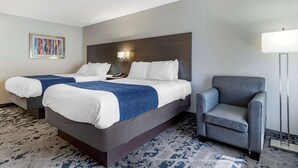 A hotel room with two beds, a grey armchair, a wall-mounted lamp, and a framed abstract painting. - Best Western Allatoona Inn & Suites (Cartersville)
