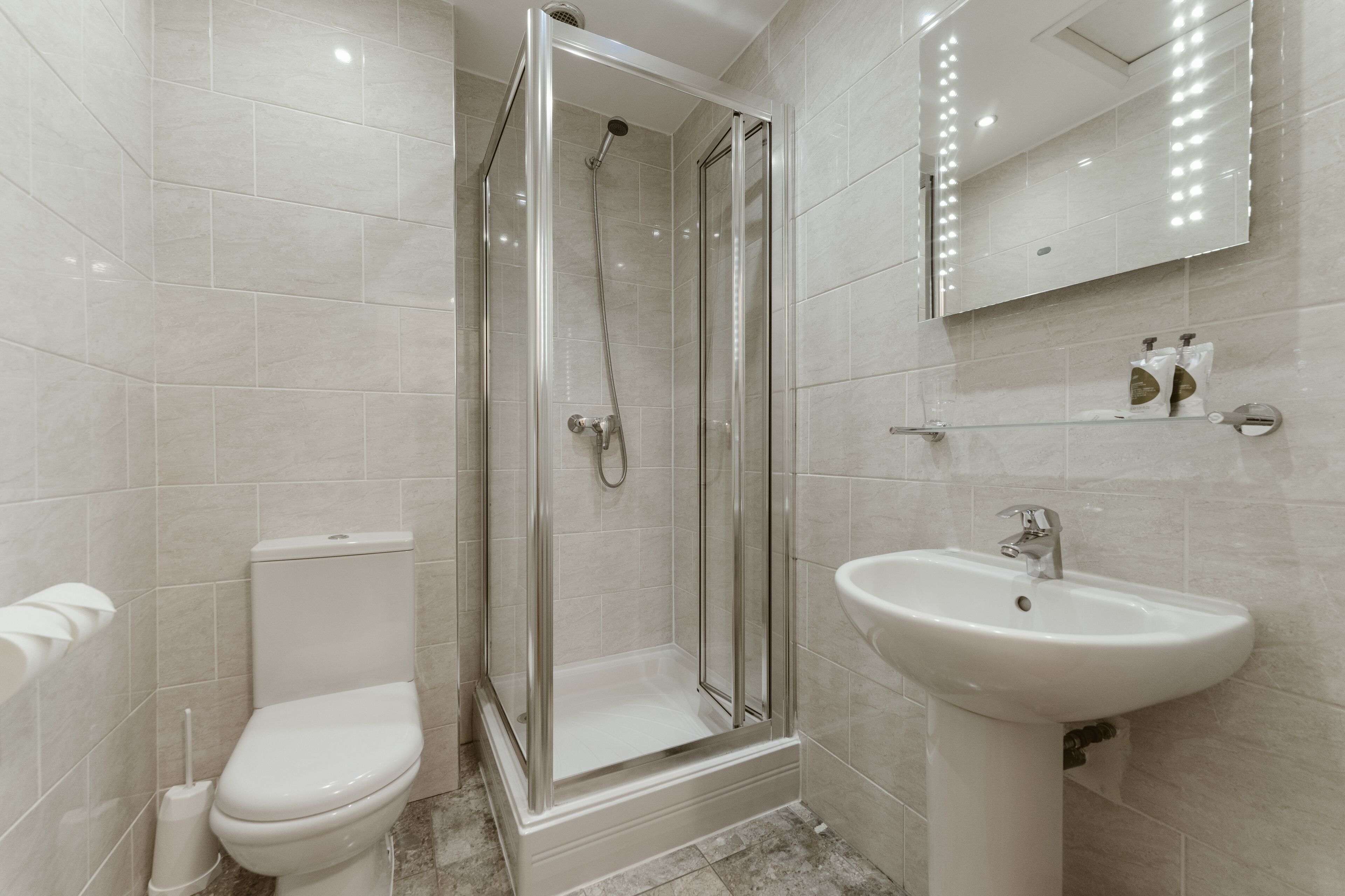 A modern bathroom with a glass-enclosed shower, a toilet, and a sink.