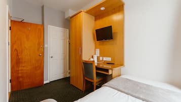 Una habitación de hotel con una cama, un escritorio con una silla, un televisor y una puerta.