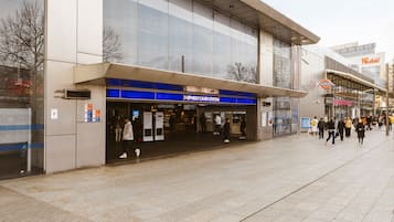 A modern building with a large glass facade, a sign for "Shepherd's Bush Station," and a visible entrance.