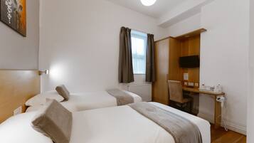 A hotel room with two beds, a desk with a chair, a television, and a window with curtains.