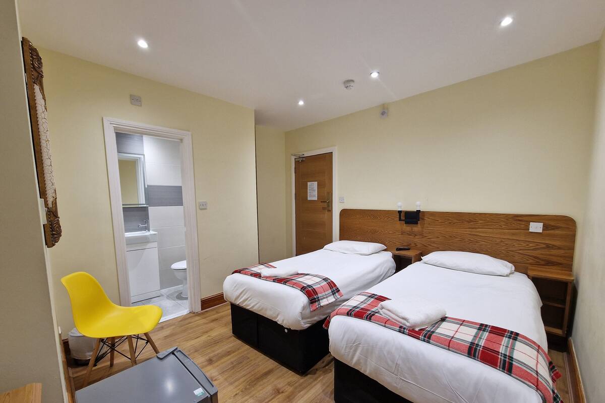 A hotel room with two beds, a desk, a chair, and a mirror.