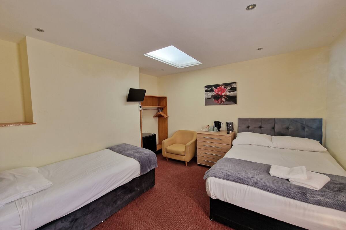 A hotel room with two beds, a desk with a computer, a chair, and a wardrobe.