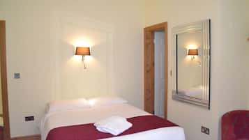 Restful retreat with a neatly made bed, wall-mounted lamps, and a mirror.
