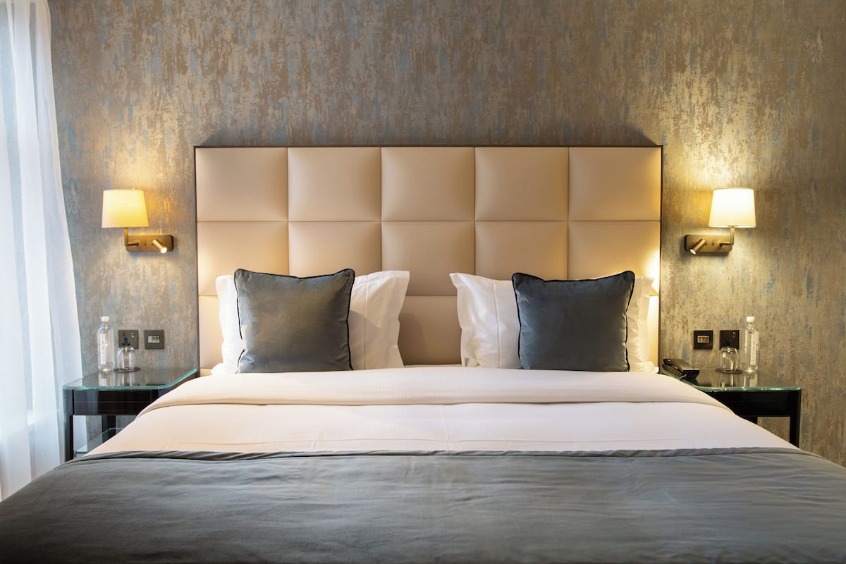 A hotel room with a large bed, two nightstands, and wall-mounted lamps.