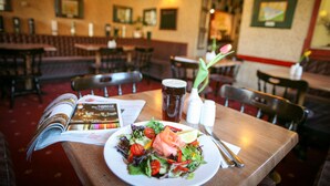A restaurant interior with a table set for a meal, including a plate of food, a menu, and a drink. - The Tomich Hotel (Beauly)