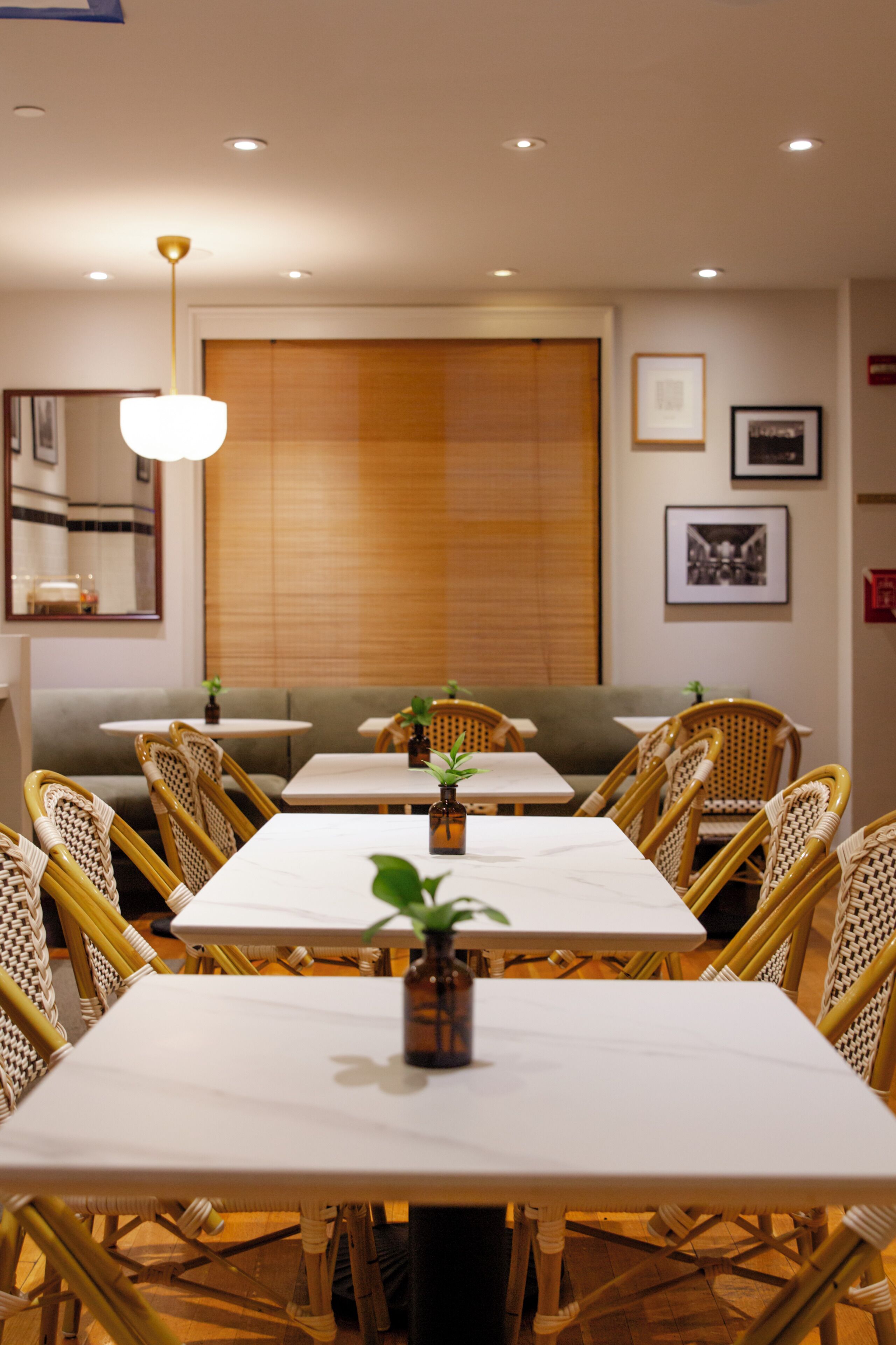 Interno di un ristorante con diversi tavoli e sedie, un'ampia finestra con vista e opere d'arte appese alle pareti.