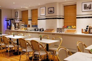 Um restaurante com um balcão comprido, cadeiras de vime e um revestimento de azulejos.