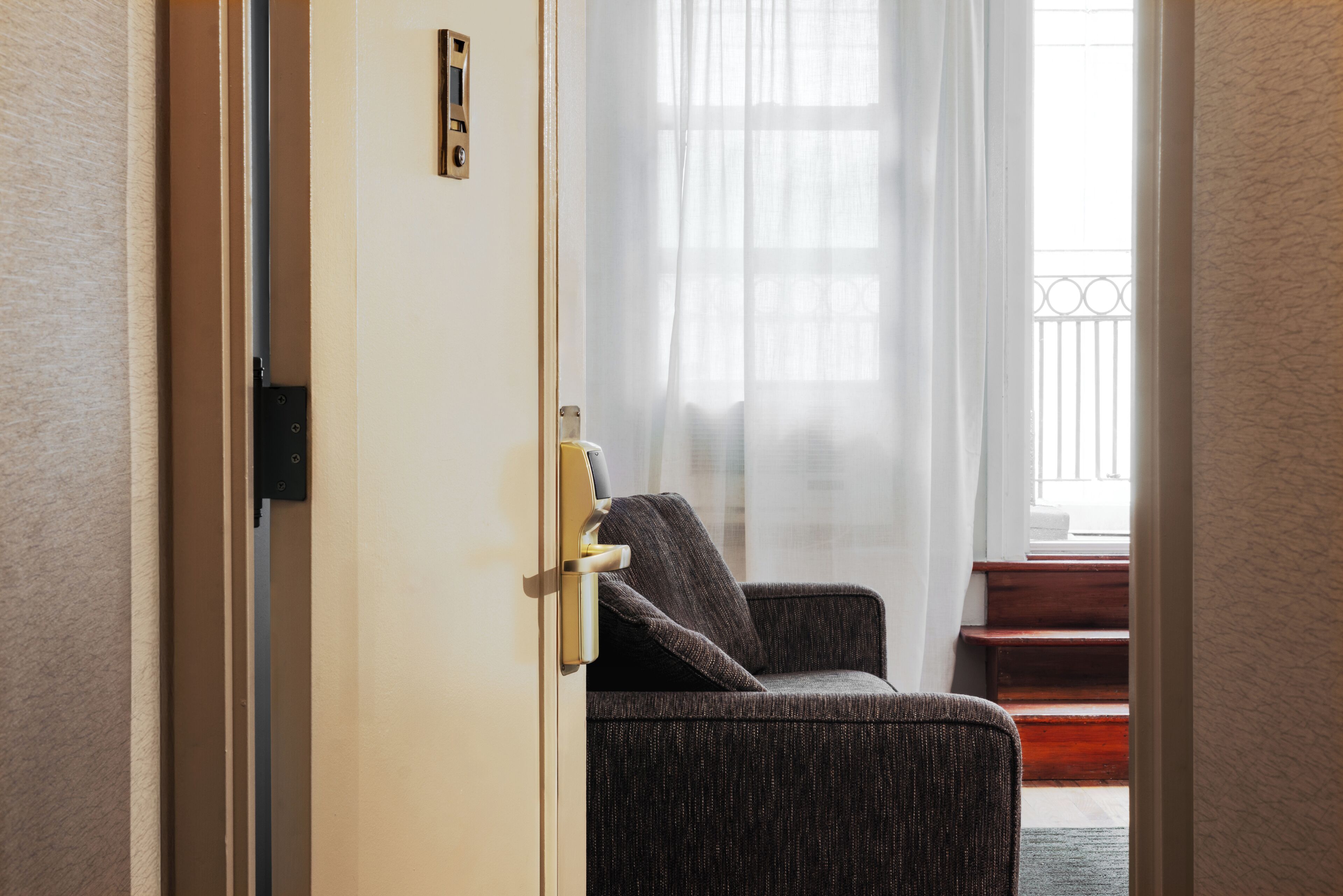 Une pièce avec une porte donnant sur un balcon, une chaise et un escalier.