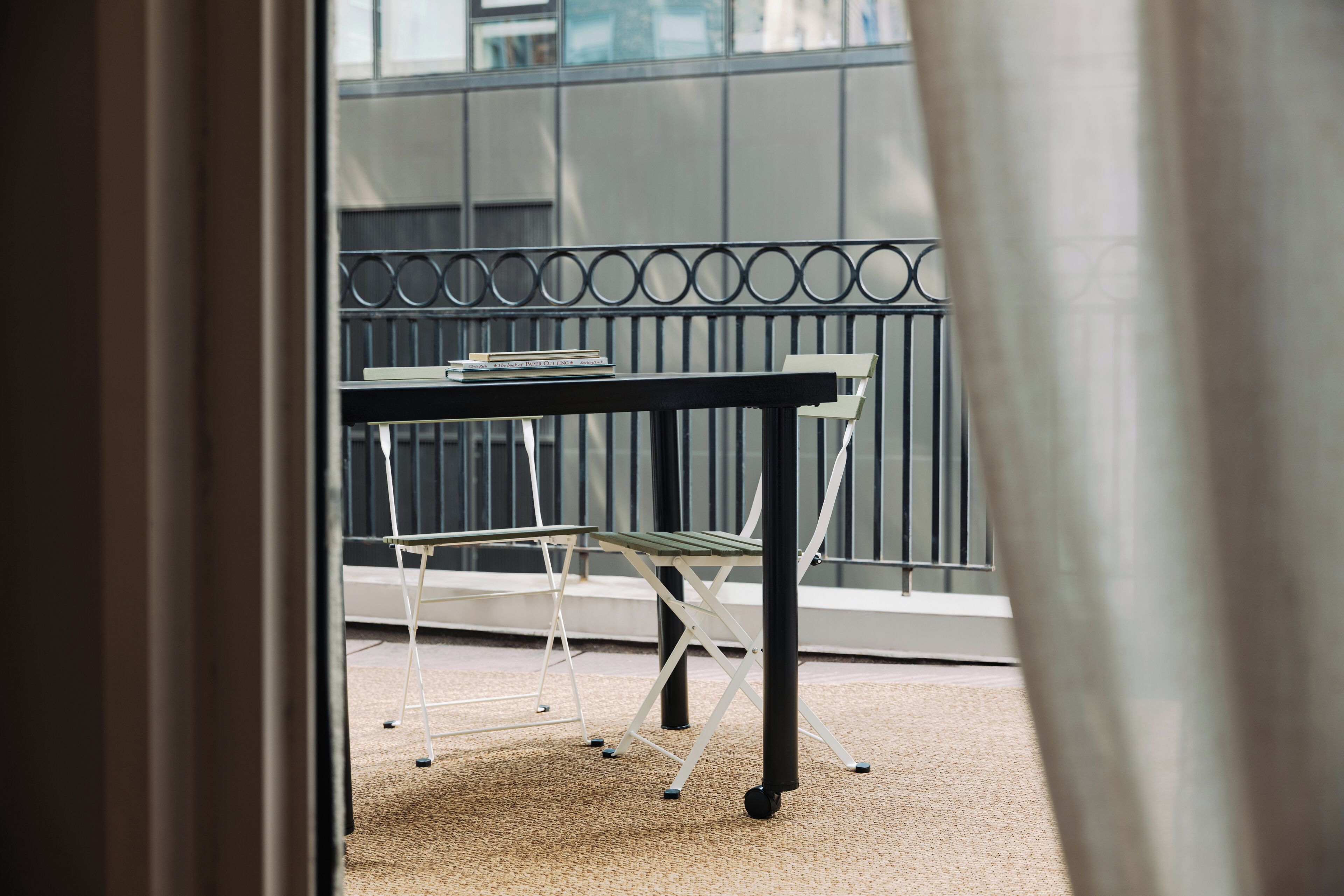 Ein Balkon mit Tisch und Stühlen, einem Metallgeländer und Blick auf ein Gebäude.