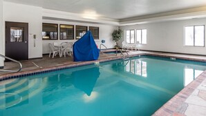 An indoor swimming pool with clear blue water, a covered seating area, and a door with a phone.