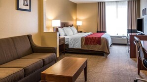 A hotel room with a bed, a sofa, a desk, a television, and a picture on the wall.