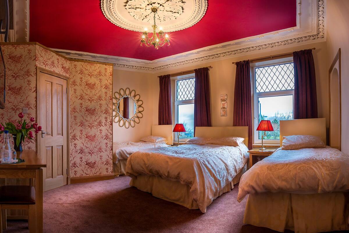 Ein Schlafzimmer mit zwei Betten, einer Kandelaber und einem großen Spiegel.