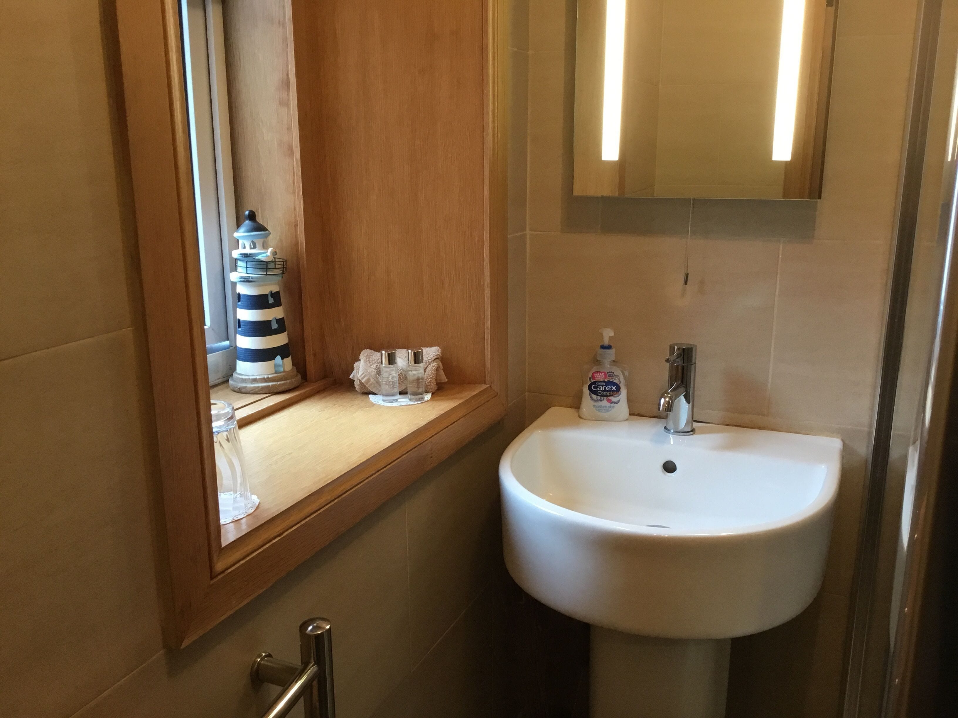 Un baño con un lavabo blanco, un espejo y una decoración de faro a rayas sobre el mostrador.