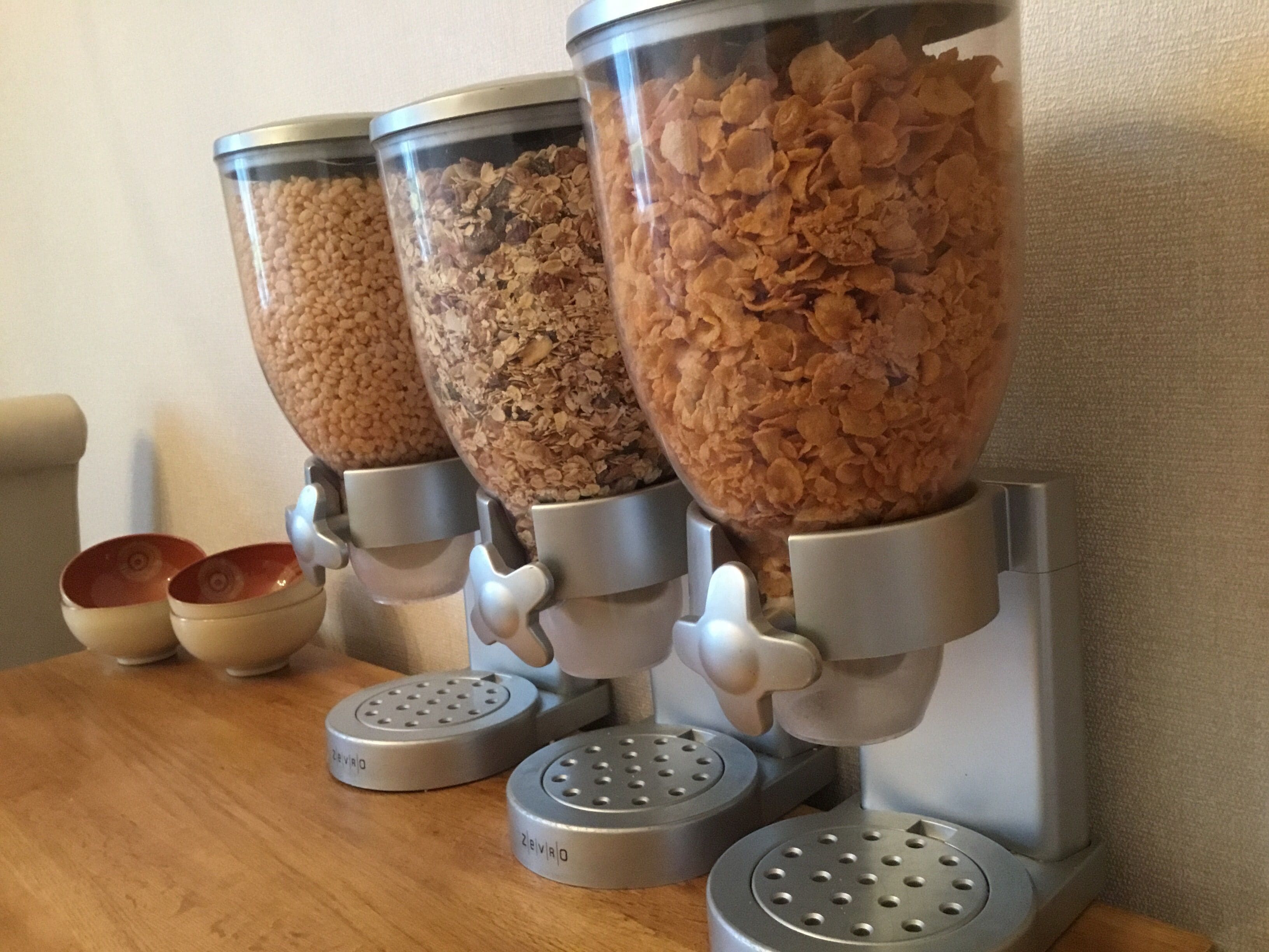 A cereal dispenser with three containers filled with cereal.