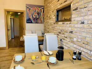 A dining area with a brick wall, a fireplace, and a colorful lion painting. - Lakeview Guest House (Stranraer)