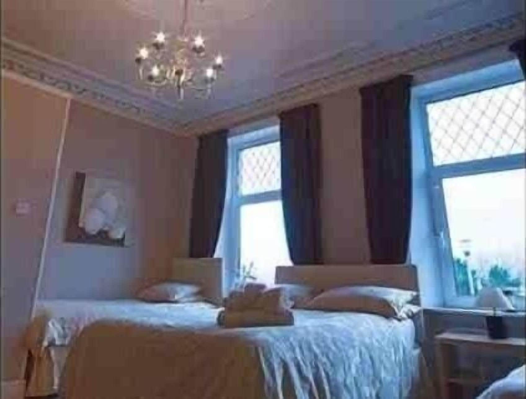Ein Schlafzimmer mit zwei Betten, einer Chandelieber und großen Fenstern.