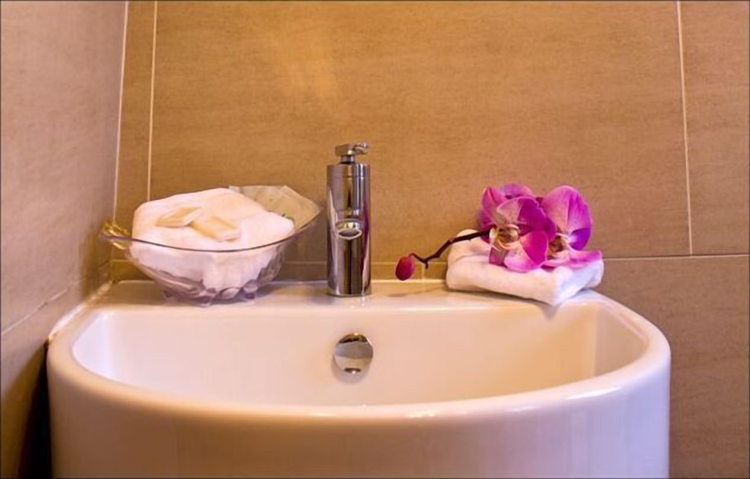 A bathroom sink with a soap dish, a faucet, and a flower arrangement.