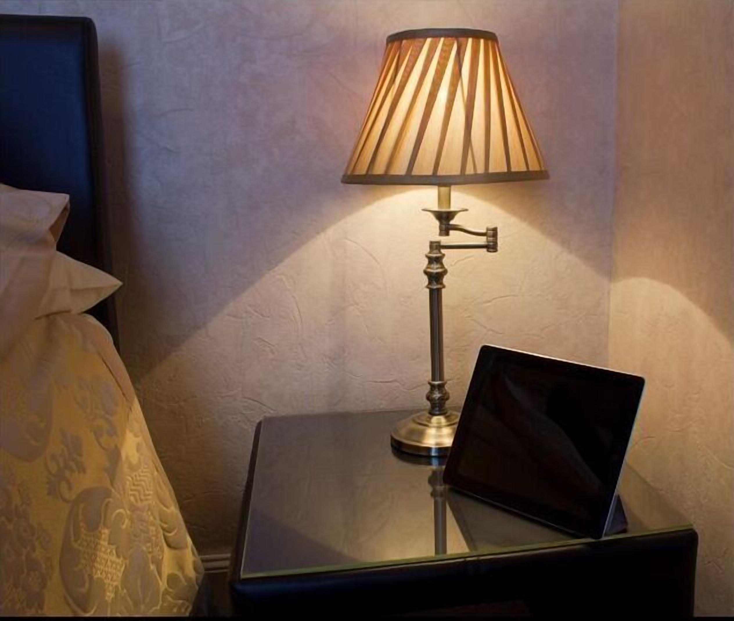 A bedside table with a lamp and a laptop.