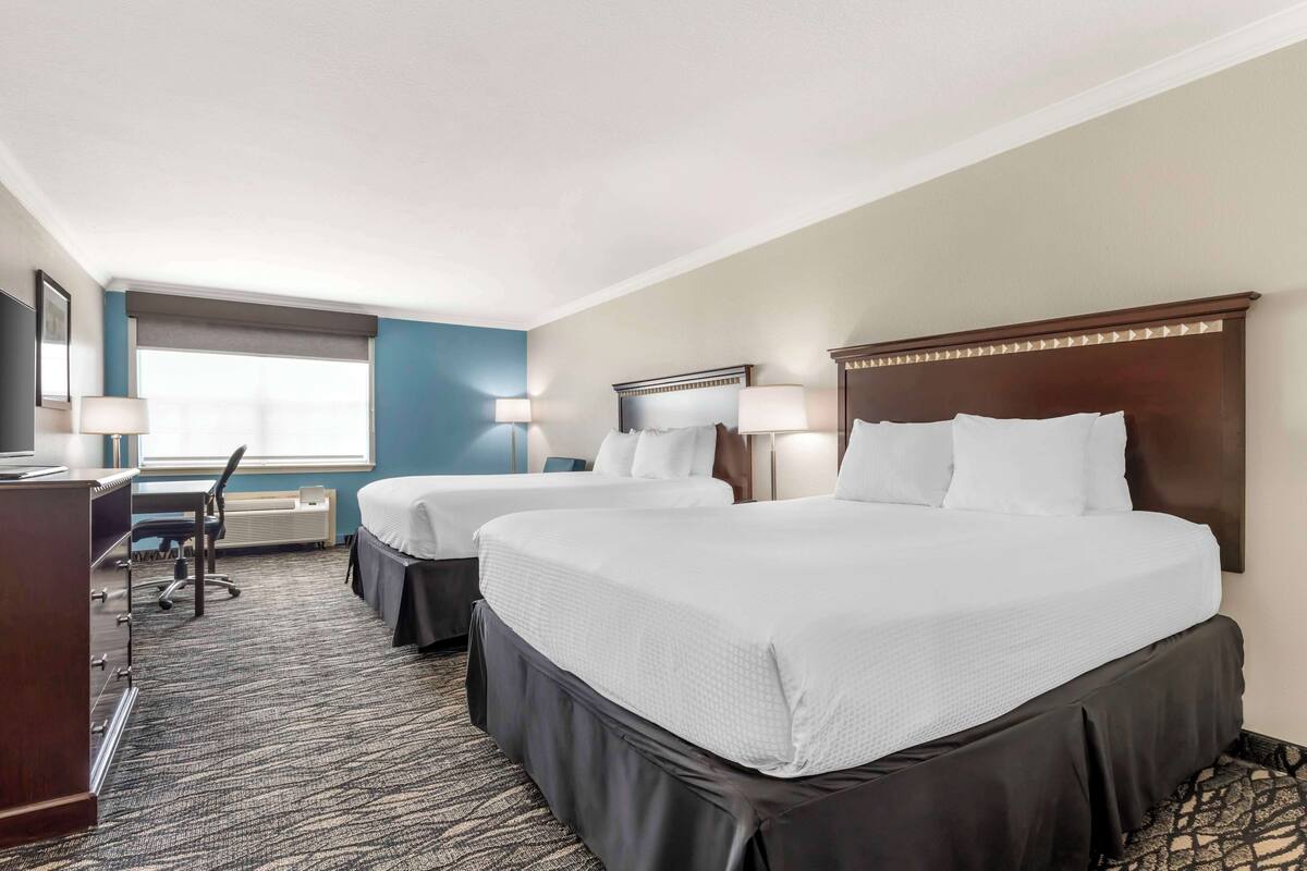 A hotel room with two beds, a desk, and a chair.