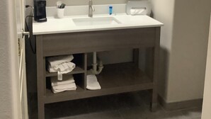 A bathroom with a white sink, a large mirror, and a towel rack. - Americas Best Value Inn & Suites San Benito (San Benito)
