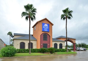 A building with a sign for "Americas Best Value Inn & Suites" featuring a red door and arched windows. - Americas Best Value Inn & Suites San Benito (San Benito)