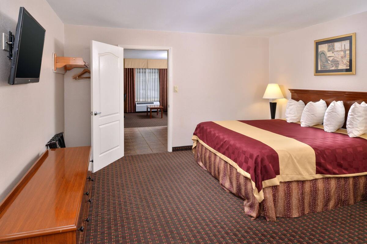 Habitación de hotel con cama, televisión, escritorio y puerta que da a un baño.