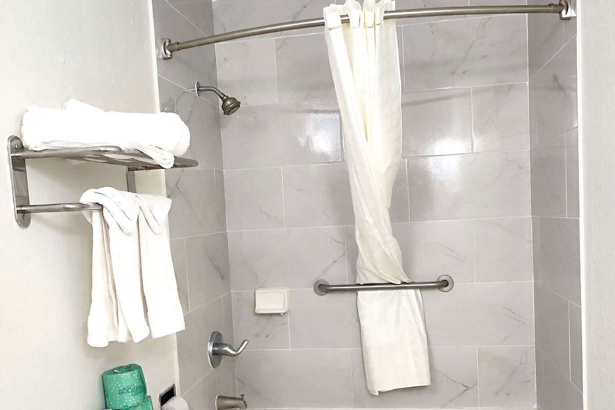 Une salle de bain comprenant des toilettes, une baignoire, une douche avec un rideau et des porte-serviettes.