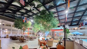 Un atrio interior con varias zonas de comedor, una piscina y un techo con diseño de cuadrícula.