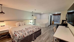 Una habitación de hotel moderna con una cama grande, un escritorio, una bañera y una zona de ducha separada.