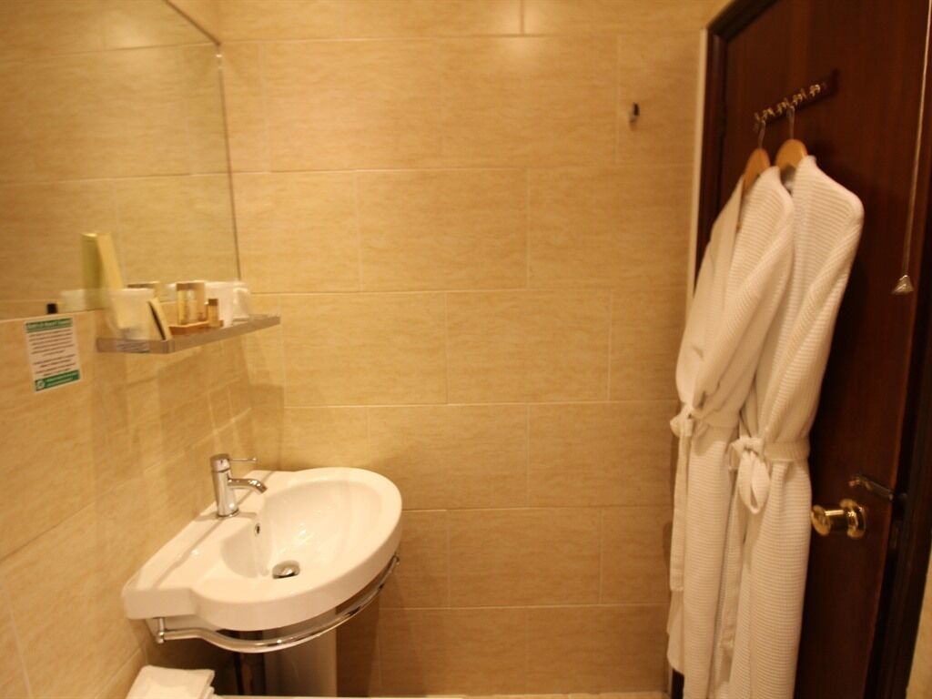 A bathroom with a sink, mirror, and a robe hanging on a door.