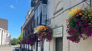 A street with a white building featuring hanging flower baskets and outdoor seating. - Pilgrims Hotel (Canterbury)