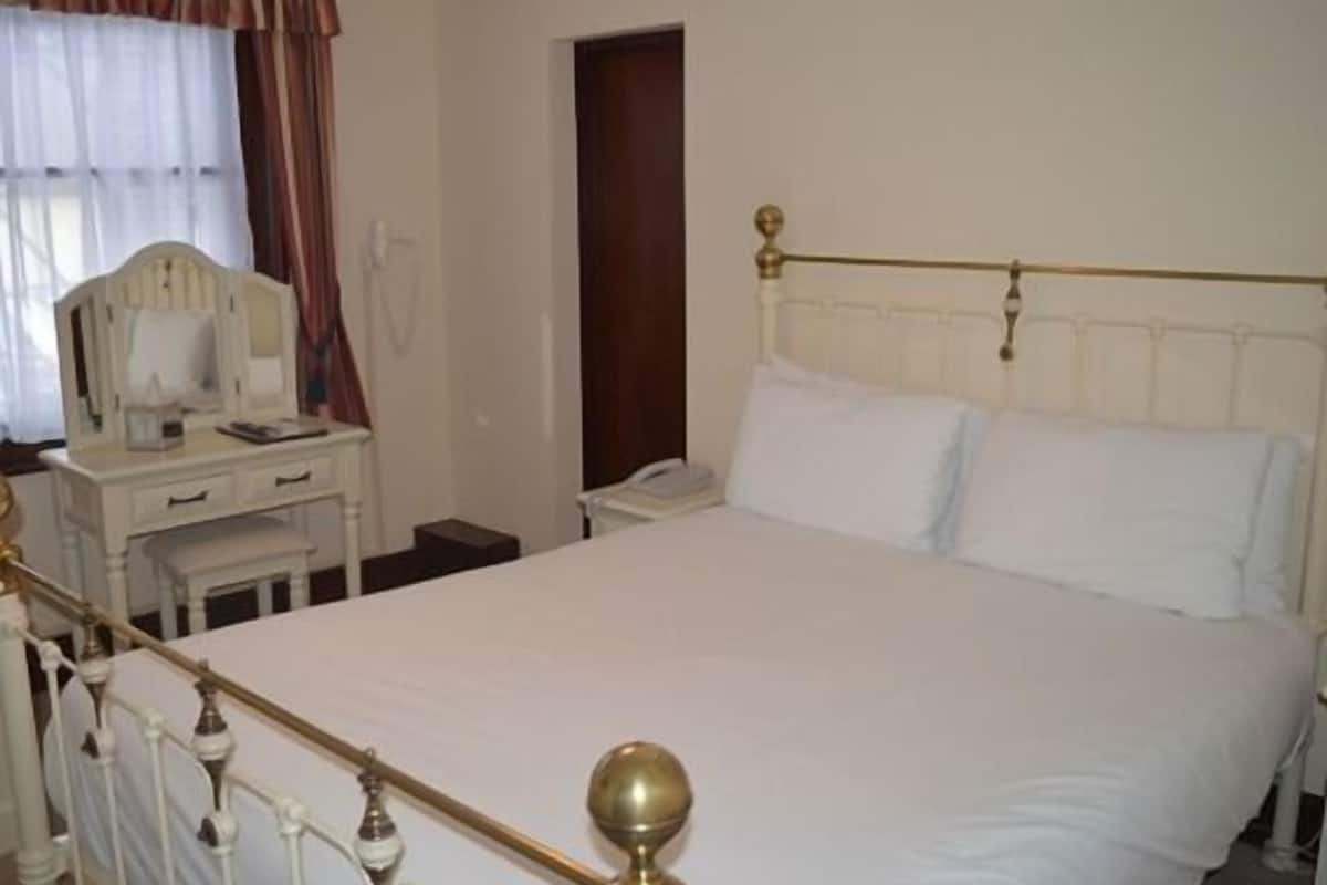 A bedroom with a bed, a bedside table, a mirror, and a wardrobe.