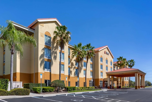 A hotel with a beige facade, multiple floors, and a covered entrance. - Comfort Inn & Suites Orlando North (Sanford)