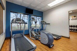 A gym with treadmills, elliptical machines, and a stair climber. There are windows with a view of trees, and a wall-mounted TV. - Comfort Inn & Suites Orlando North (Sanford)