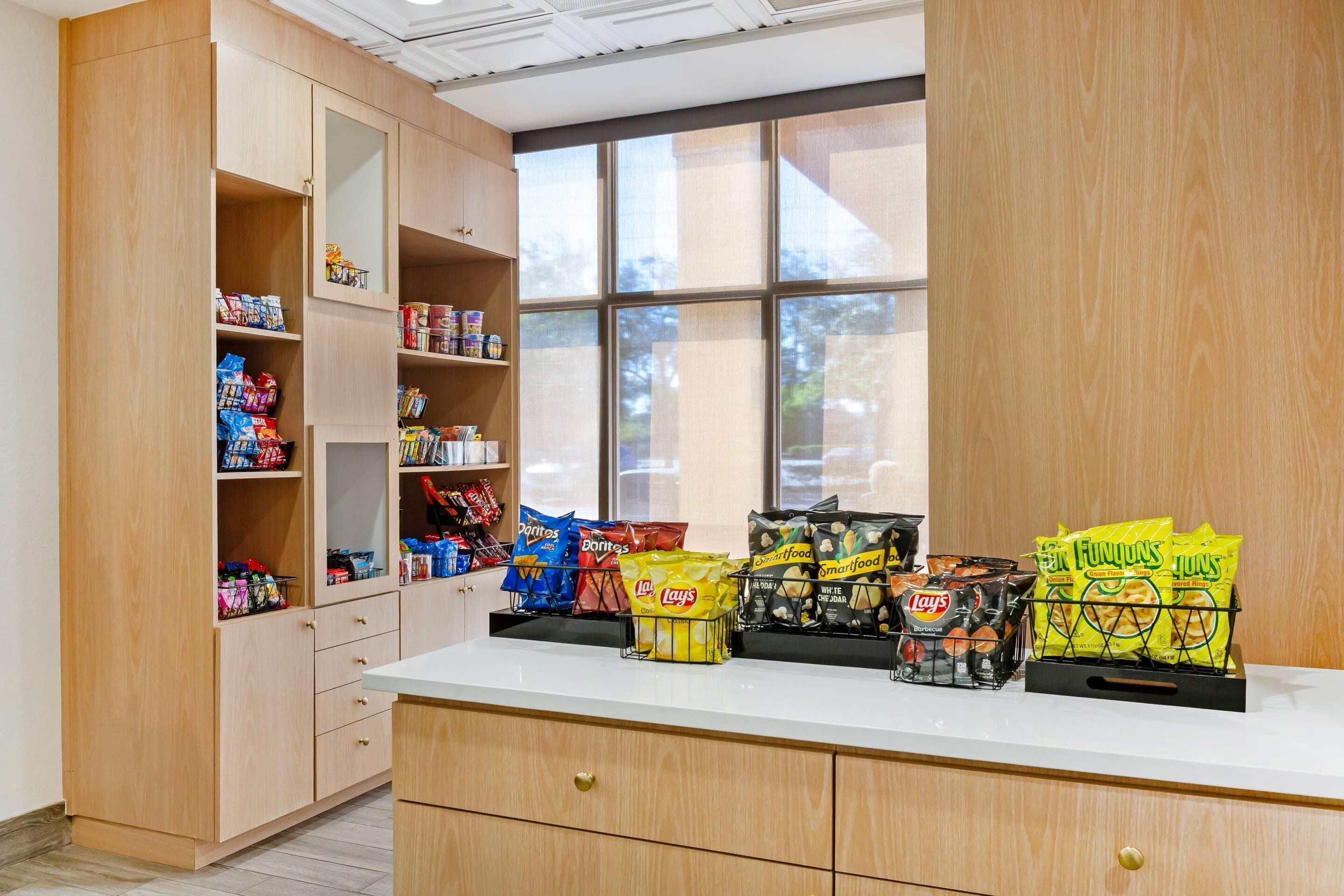 Ein Imbissstand mit verschiedenen verpackten Snacks und einem Fenster mit Blick auf Bäume.