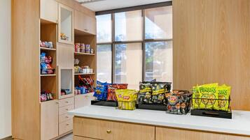 Ein Imbissstand mit verschiedenen verpackten Snacks und einem Fenster mit Blick auf Bäume.