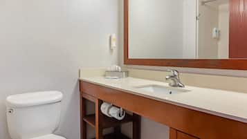 A bathroom with a white toilet, a wooden vanity with a sink, and a mirror above the vanity.