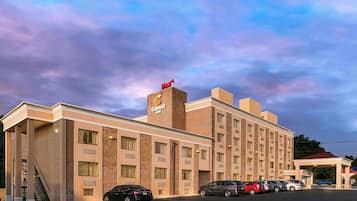 Un hotel Comfort Inn con fachada de ladrillo, varias ventanas y un estacionamiento con varios coches.