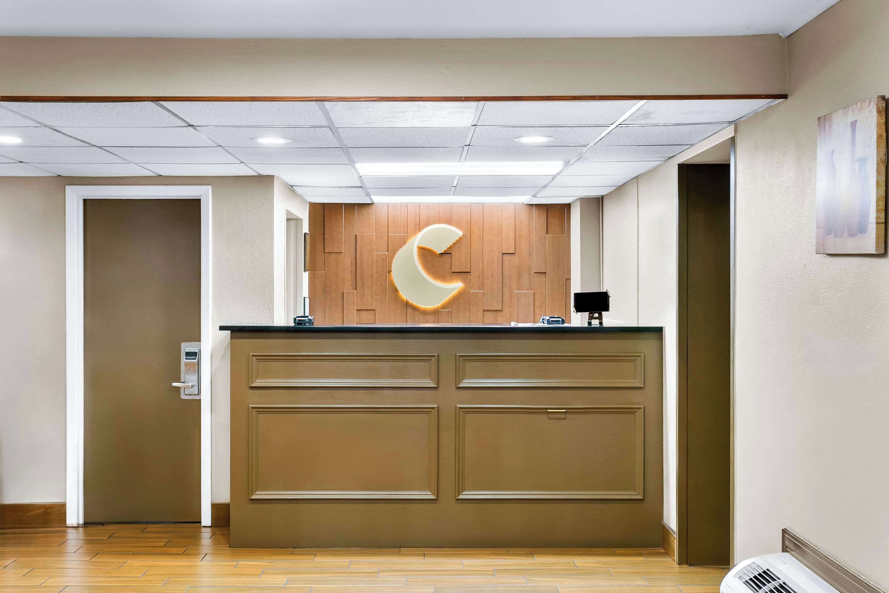 A reception area with a wooden panel wall, a counter with a crescent moon design, and a door to the left.