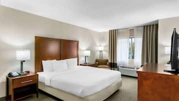 A hotel room with a large bed, bedside tables with lamps, a desk, and a television.